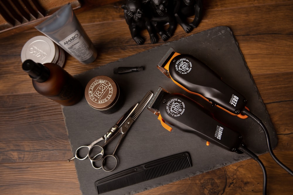 Barber tools on a slate slab, including clippers, scissors, a comb, and grooming products